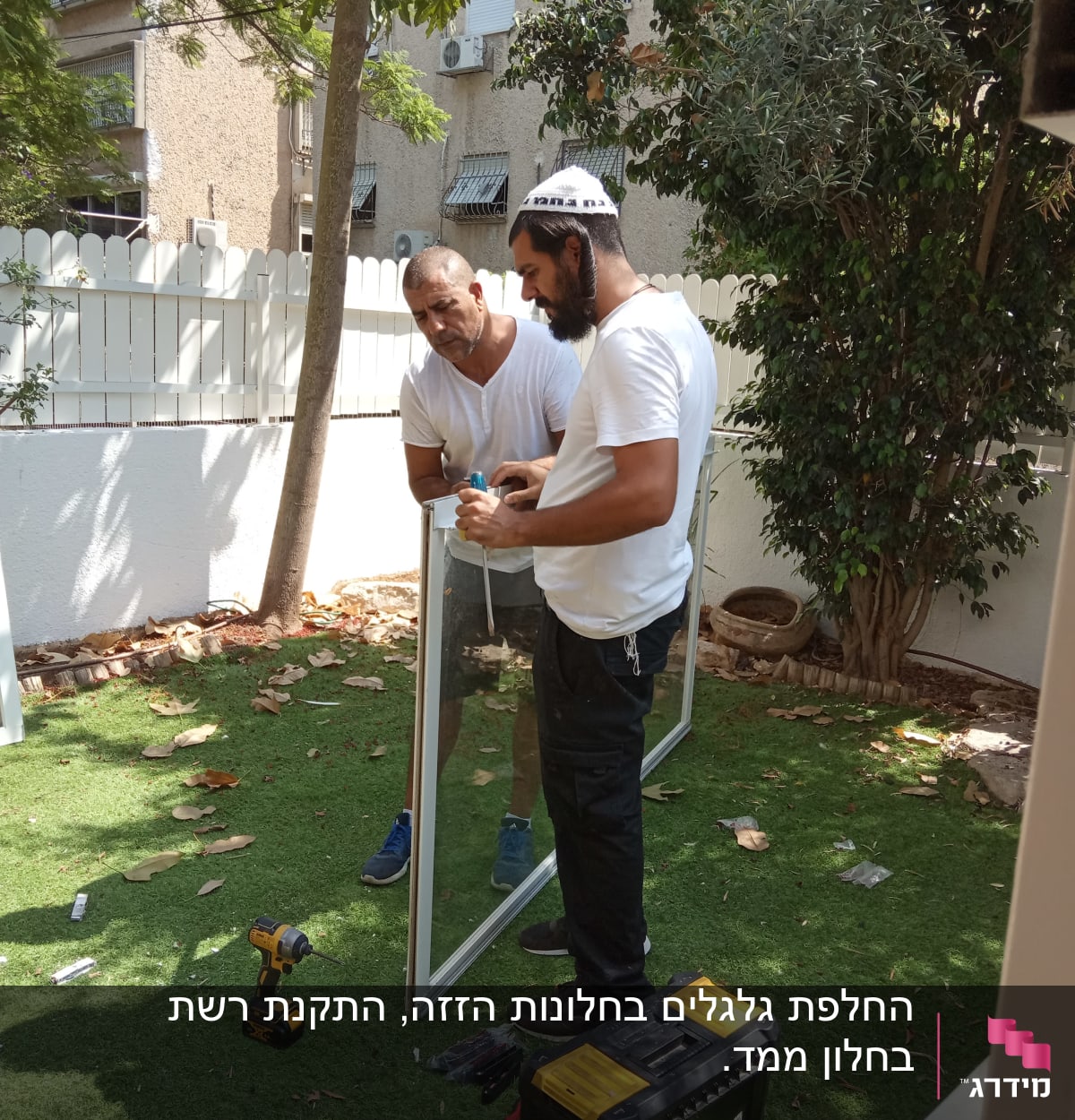 שני אנשים מתקנים תריסים עם כלים בחצר